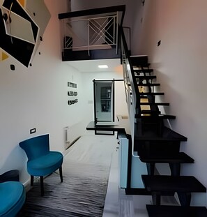 A modern interior with a staircase, a seating area with chairs, and a wall with text. - Okeyloft 3 Coyhaique (Coyhaique)