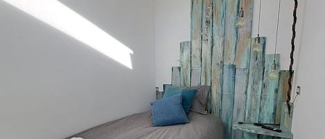 A bedroom with a bed, pillows, a wall-mounted light fixture, and a rug.