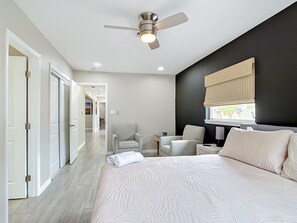 Ein modernes Hotelzimmer mit einem großen Bett, einem Deckenventilator, einem Schreibtisch und einem Stuhl.
