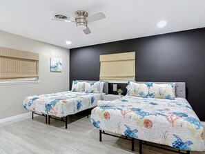 Un dormitorio con dos camas, un ventilador de techo y una ventana con persianas.