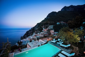 A coastal hotel with a pool, lounge chairs, and a view of the sea and mountains. - Villa Evia by My Villa Collection (Positano)