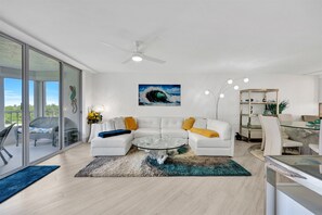 A modern living room with a glass coffee table, white sofas, and a ceiling fan. - 2-bedroom condo in brilliant, completely renovated in 2026 Naples with cool AC (Naples)