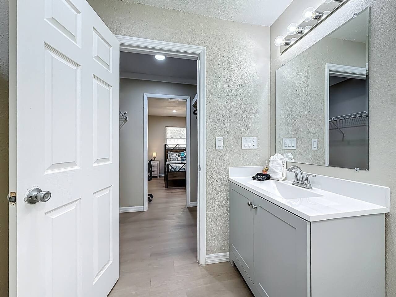A bathroom with a white vanity, a large mirror, and a walk-in shower.