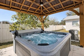 A hot tub under a wooden pergola in a backyard with a white fence and a house in the background. - Clearwater Getaway Retreat 6BR 4BA Sleep 18 (Largo)