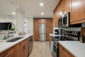 A modern kitchen with stainless steel appliances, wooden cabinets, and a tiled floor. - Siesta Key Paradise 5BR 4BA Sleep 20 (Sarasota)