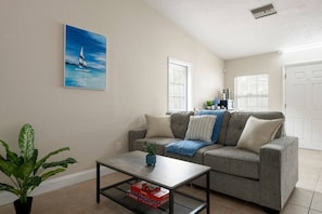 A living room with a grey sofa, a coffee table, a painting, and a potted plant. - Siesta Key Paradise 5BR 4BA Sleep 20 (Sarasota)