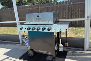 Een kolengrill met bedieningspaneel, een brandstofbus en een schoonmaakborstel.