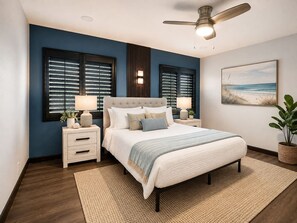 A bedroom with a bed, nightstands, a ceiling fan, and a beach-themed painting.