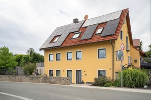 A yellow building with a sloped roof, multiple windows, and a speed limit sign.