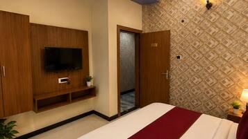 Una habitación de hotel moderna con cama, televisor, ventilador de techo y pared con diseño.