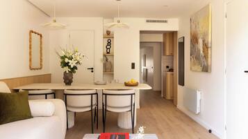 Una cocina moderna con una isla central, sillas de comedor, un sofá y una mesa de centro con libros.
