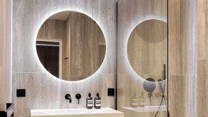 Un bagno moderno con un mobile lavabo, due specchi, una doccia e un angolo doccia con pareti in vetro.
