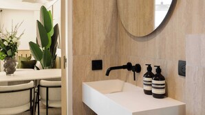 Un bagno moderno con un mobile lavabo bianco, uno specchio rotondo e un porta asciugamani.