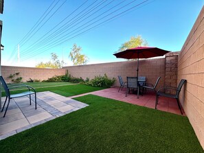 Un espace patio avec une table et des chaises, un parasol rouge et un mur en briques.