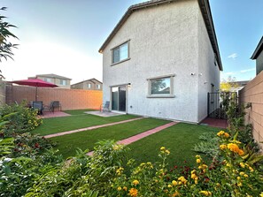 Une maison à deux étages avec un patio, un parasol rouge et un mur en briques.