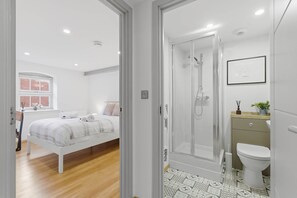 A modern bedroom with a bed, a bedside table, and a window with a view of a brick wall. - The Cosy City Apartment of Lichfield (Lichfield)