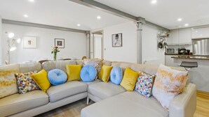 Ein modernes Wohnzimmer mit einer Eckcouch, einem Essbereich und einer Küche mit Edelstahlgeräten.