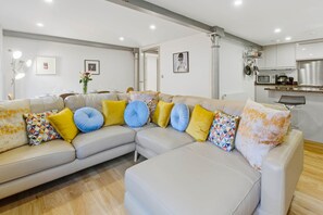 A modern living room with a sectional sofa, a dining area, and a kitchen with stainless steel appliances. - The Cosy City Apartment of Lichfield (Lichfield)
