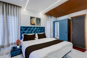 Ein modernes Schlafzimmer mit einem großen Bett, einem blauen Kopfteil und einem Nachttisch mit Blumen.