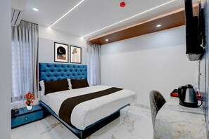 Ein modernes Hotelzimmer mit einem großen Bett, einem Schreibtisch, einem Wasserkocher und einem Fernseher.