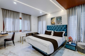 Ein modernes Hotelzimmer mit einem großen Bett, einem Schreibtisch mit Stuhl, einem kleinen Beistelltisch und einer dekorativen Vase mit Blumen.