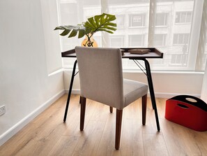 Een stoel met een gestructureerde rugleuning en houten poten, geplaatst voor een tafel met een plant erop.