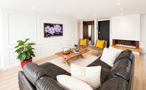 A modern living room with a leather sofa, a wooden coffee table, and a large flat-screen TV mounted on the wall. - Apartamento Premium/a pasos de la Zona t /Parque 93/100mt (Bogotá, D.C.)
