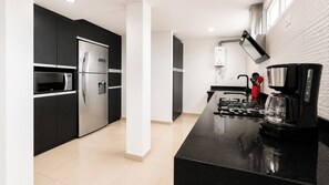 Et moderne køkken med sorte skabe, rustfrie stål hvidevarer og en sort bordplade.