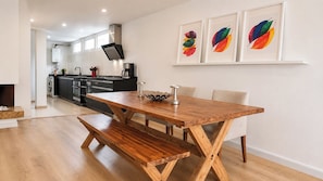 A modern kitchen with a wooden dining table and bench, a coffee maker, and a TV. - Apartamento Premium/a pasos de la Zona t /Parque 93/100mt (Bogotá, D.C.)