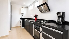 A modern kitchen with a built-in washer, a stove, and a coffee maker. - Apartamento Premium/a pasos de la Zona t /Parque 93/100mt (Bogotá, D.C.)