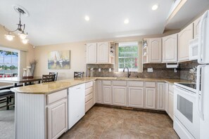 A modern kitchen with white cabinetry, a granite countertop, and a built-in dishwasher. - Goguac Lake House|Sleeps6|Private Dock|Boat Launch (Battle Creek)