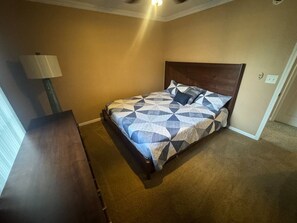 Un dormitorio con cama, mesita de noche y lámpara.