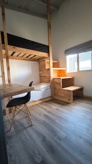 Ein Zimmer mit einem Etagenbett, einem Schreibtisch und einem Stuhl.