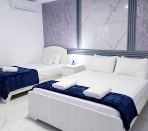 A hotel room with two beds, a nightstand, and a large window with a marble design. - Sol Caribe Bar on the Beach (Punta Cana)