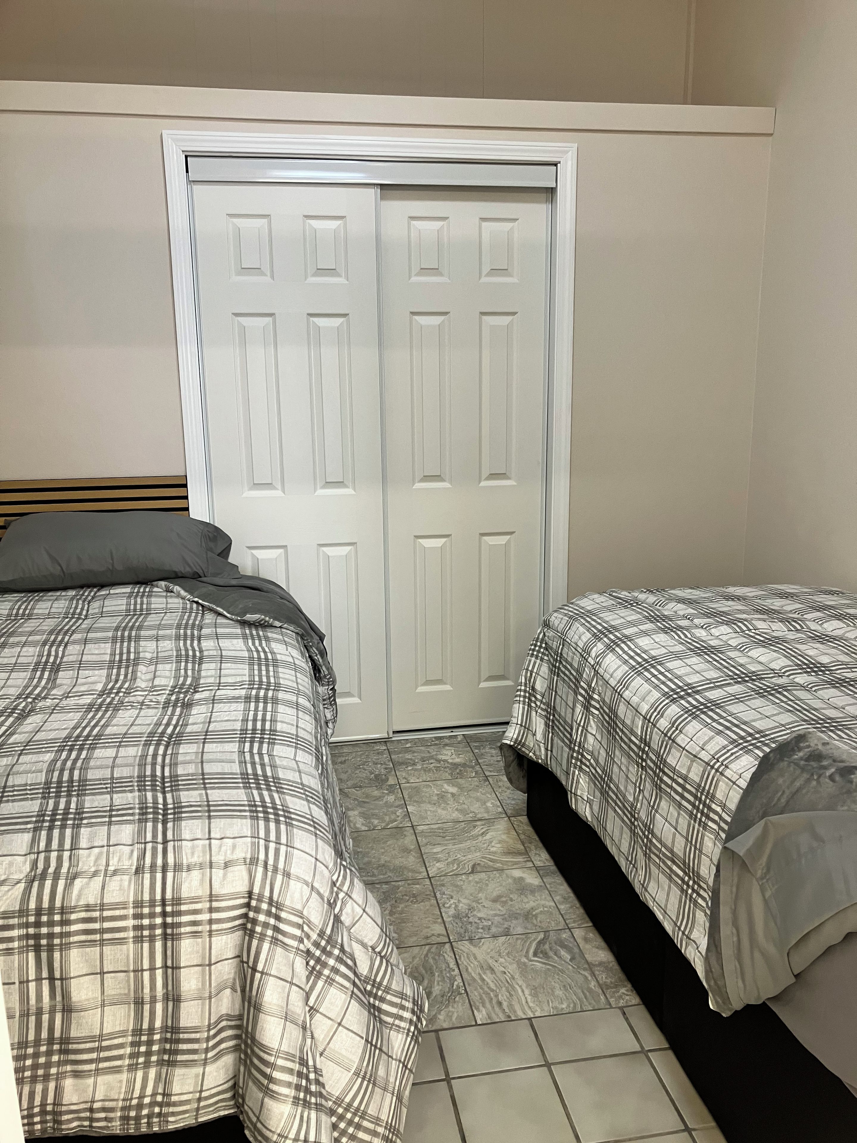 Un dormitorio con dos camas, un armario y piso de baldosas.