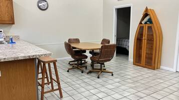 Une pièce de taille modeste comprenant un coin cuisine, une table à manger avec des chaises, un meuble en bois et une horloge au mur.