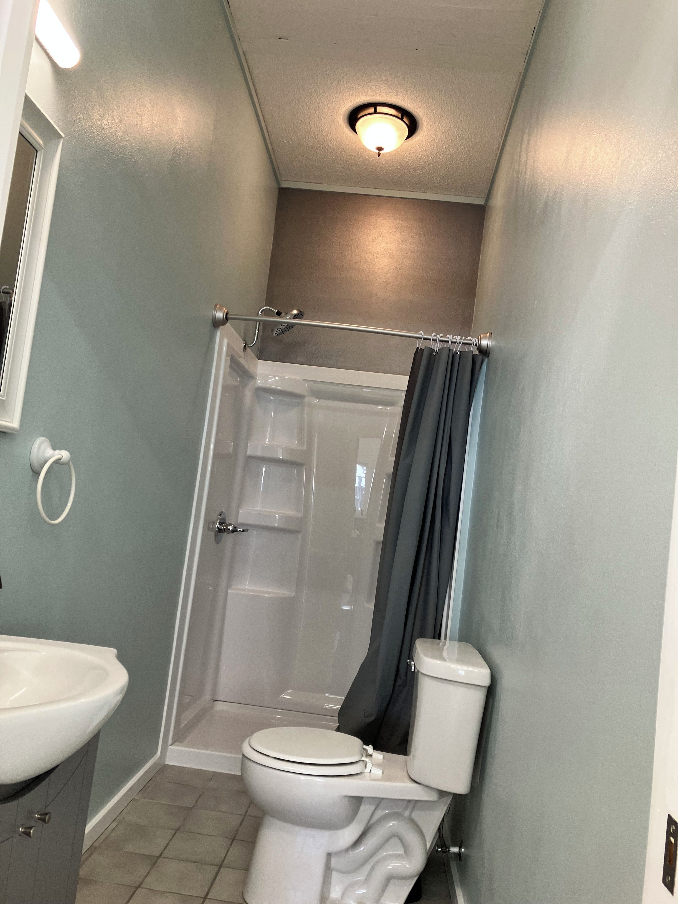 Une salle de bain avec douche, toilettes et lavabo.