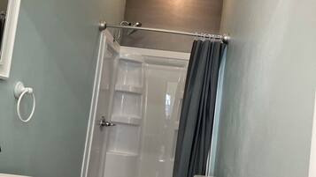 Une salle de bain avec douche, toilettes et lavabo.