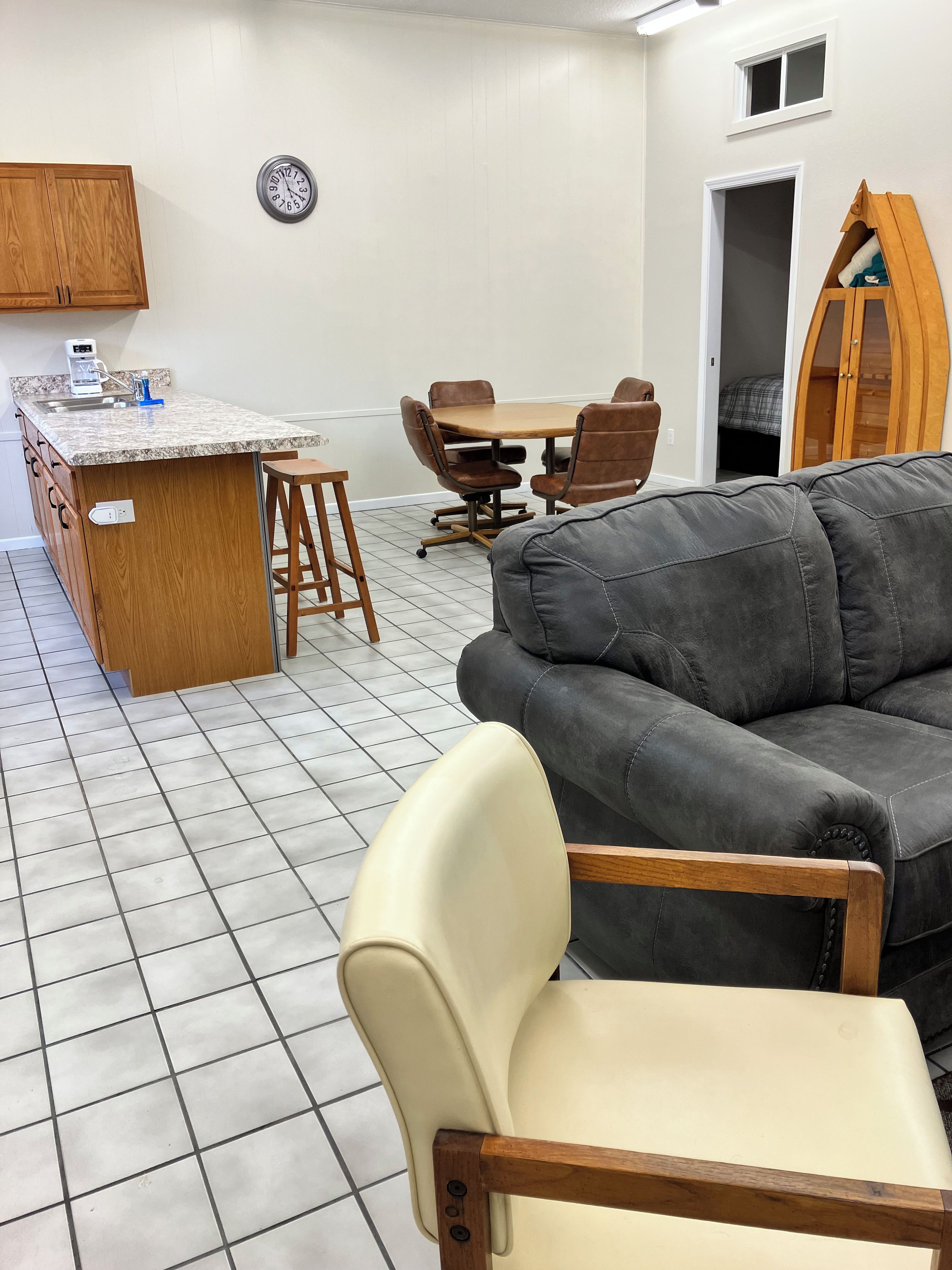 Una cocina moderna con una isla integrada, un comedor con mesa y sillas de madera, y un sofá gris.