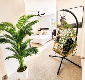 A bedroom with a bed, a hanging chair with plants, a ceiling fan, and a wall-mounted artwork. - Luxury 5BR Furnished Spacious Dallas Retreat. Short & Extended Stays. Sleeps 16! (Glenn Heights)