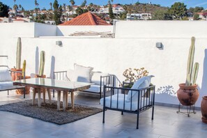 An outdoor patio with a table and chairs, surrounded by potted plants. - Private+Home+Oceanviews+Pool+Jacuzzi Getaway Near Valle de Guadalupe (Ensenada)