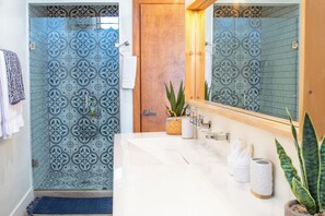 Ein Badezimmer mit Dusche, Waschbecken und Spiegel.