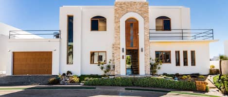 A modern two-story house with a stone facade, a wooden front door, and a garage.