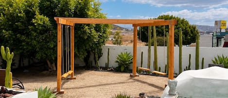 A backyard with a wooden pergola, a swimming pool, and a well-maintained lawn.