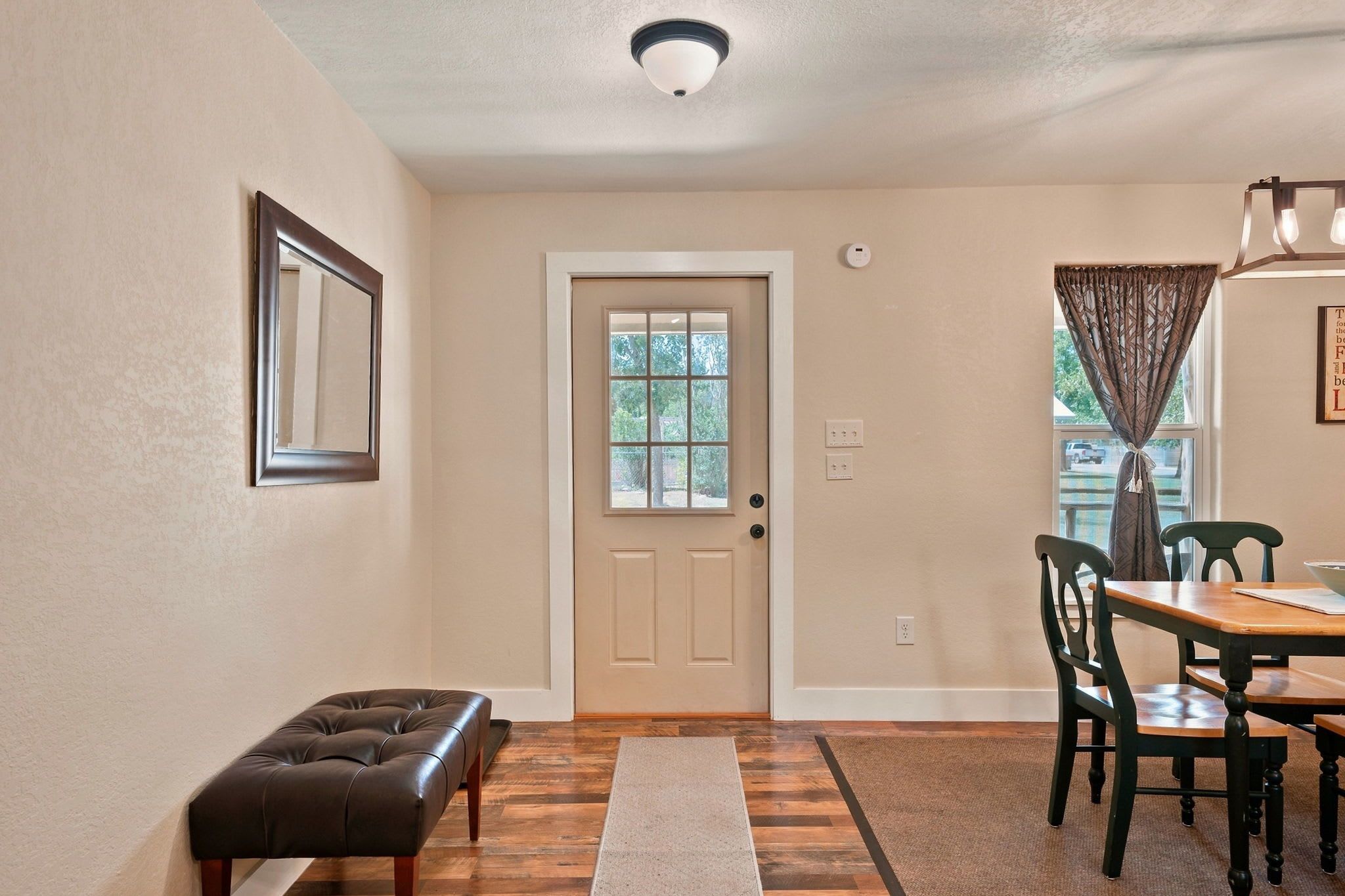 A dining area with a wooden table and chairs, a bench, and a door with a window.
