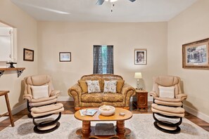 A living room with a sofa, two armchairs, a coffee table, and a side table with a lamp.