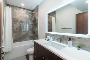 Ein modernes Badezimmer mit Badewanne, Toilette und Waschtisch mit Spiegel.