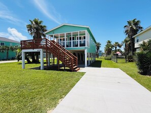 A two-story building with a covered porch and a wooden staircase. - 3 Bedroom/Sleeps 7/Sea Isle/pool access (Galveston)