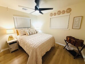 A bedroom with a bed, nightstands, a suitcase, and a ceiling fan. - 3 Bedroom/Sleeps 7/Sea Isle/pool access (Galveston)
