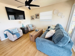 A living room with a sofa, a coffee table, a TV, and a ceiling fan. - 3 Bedroom/Sleeps 7/Sea Isle/pool access (Galveston)